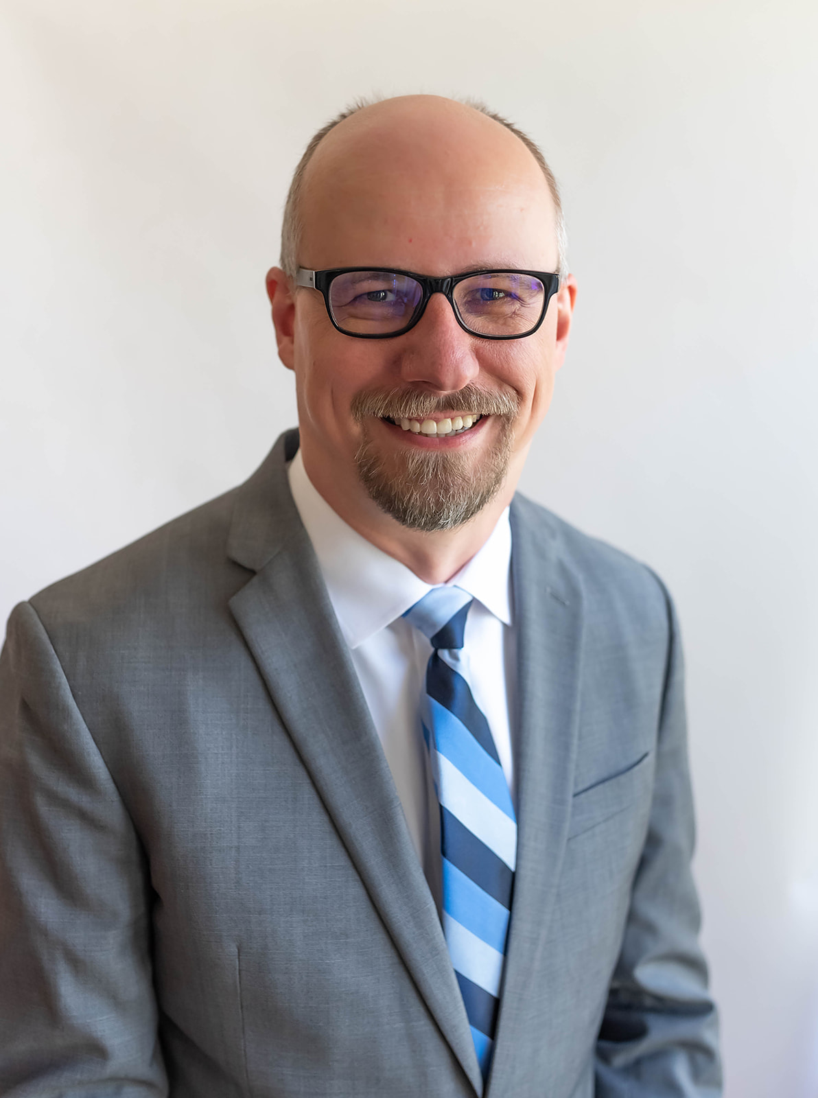 A headshot of Eric Wall, a bald man in a gray suit.