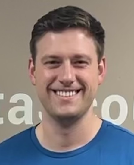 A headshot of a clean-shaven white man wearing a blue t-shirt.